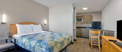 A bedroom with a bed, bedside table, and a small desk area with a chair.