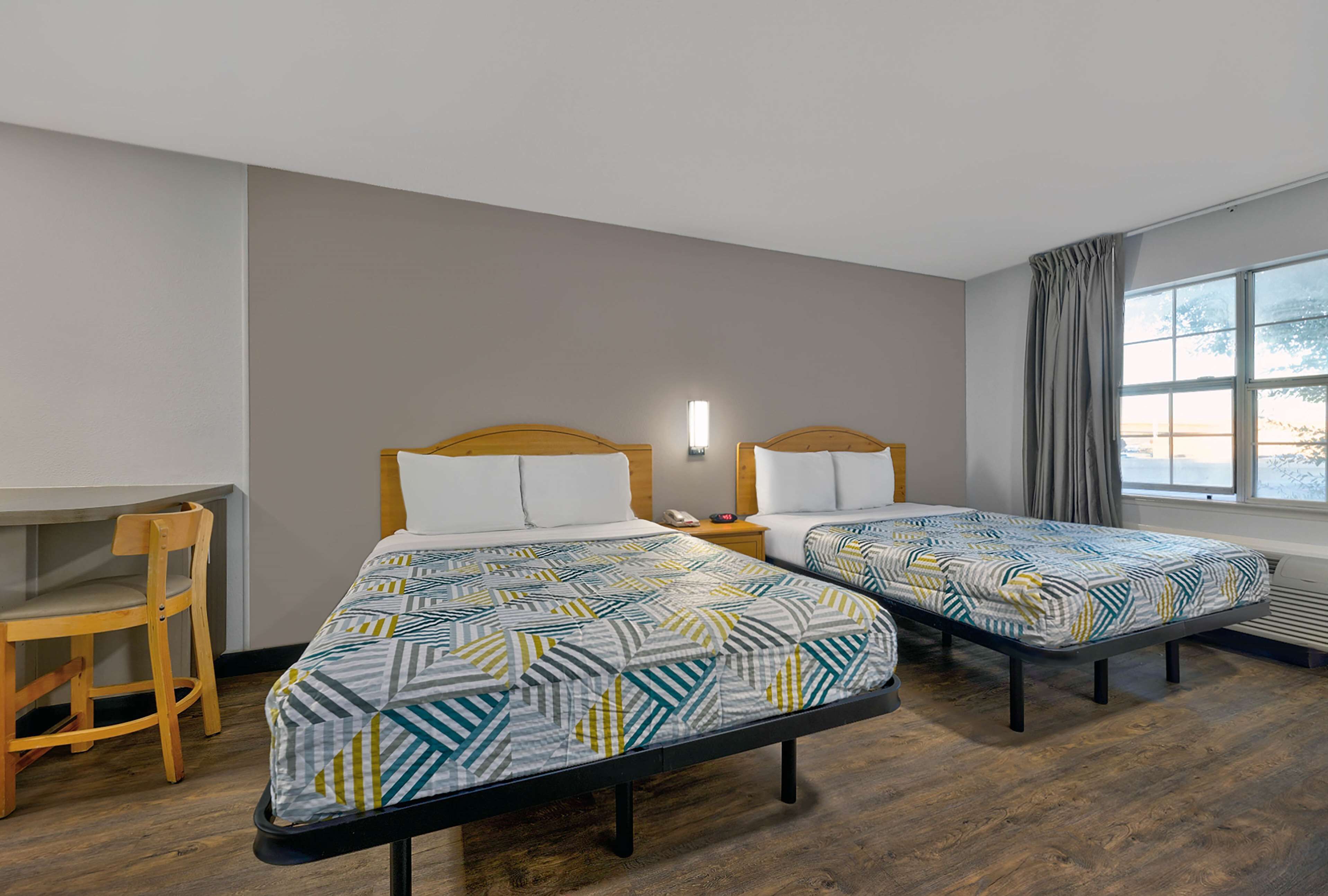 A room with two single beds, a desk, and a chair.