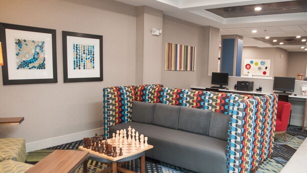 A modern lounge area with a sofa, a chess table, and artwork on the walls.