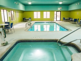 Zona de piscina con dos piscinas, sillas y mesas.