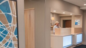 A reception area with a wooden door, a reception desk, and a framed abstract artwork on the wall.