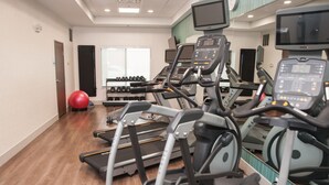 A gym with treadmills, exercise balls, and dumbbells.