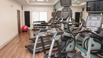 Un gimnasio con cintas de correr, pelotas de ejercicio y mancuernas.