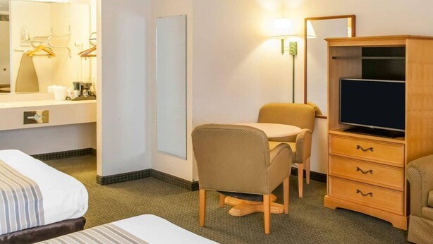 A hotel room with a bed, a desk with a chair, a television, and a wardrobe.