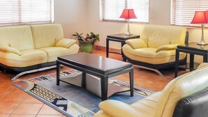 A living room with two yellow leather sofas, a coffee table, and two lamps. There is a potted plant on the floor.