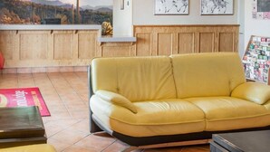 A yellow leather sofa in a room with wooden paneling, a kitchen area with a view, and framed artwork on the wall.