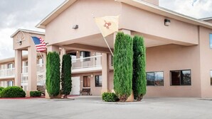 A hotel with a flat roof, a central entrance, and a flagpole with an American flag.