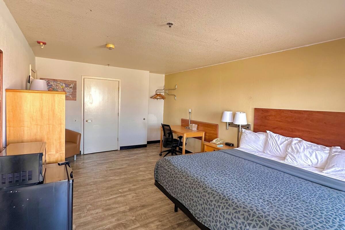 Una habitación de hotel con cama, escritorio, silla y armario.