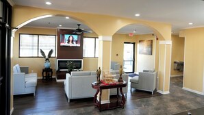 A spacious lobby with a modern design, featuring a large sofa, a coffee table, and a television mounted on the wall. - Baymont by Wyndham Manning (Manning)