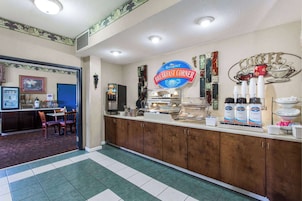 Una barra de desayuno con un letrero que dice "Baymont Breakfast Corner", que incluye una estación de café con tazas y una cafetera.