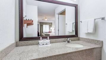 Un baño con un espejo grande, encimera de granito y un lavabo.