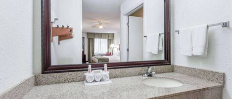 A bathroom with a large mirror, granite countertop, and a sink.