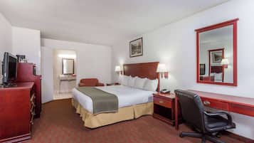 Habitación de hotel con cama, escritorio, silla, cómoda y espejo.