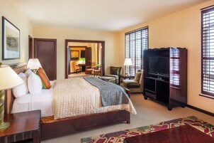 Una habitación de hotel con una cama grande, televisión, escritorio y una silla.
