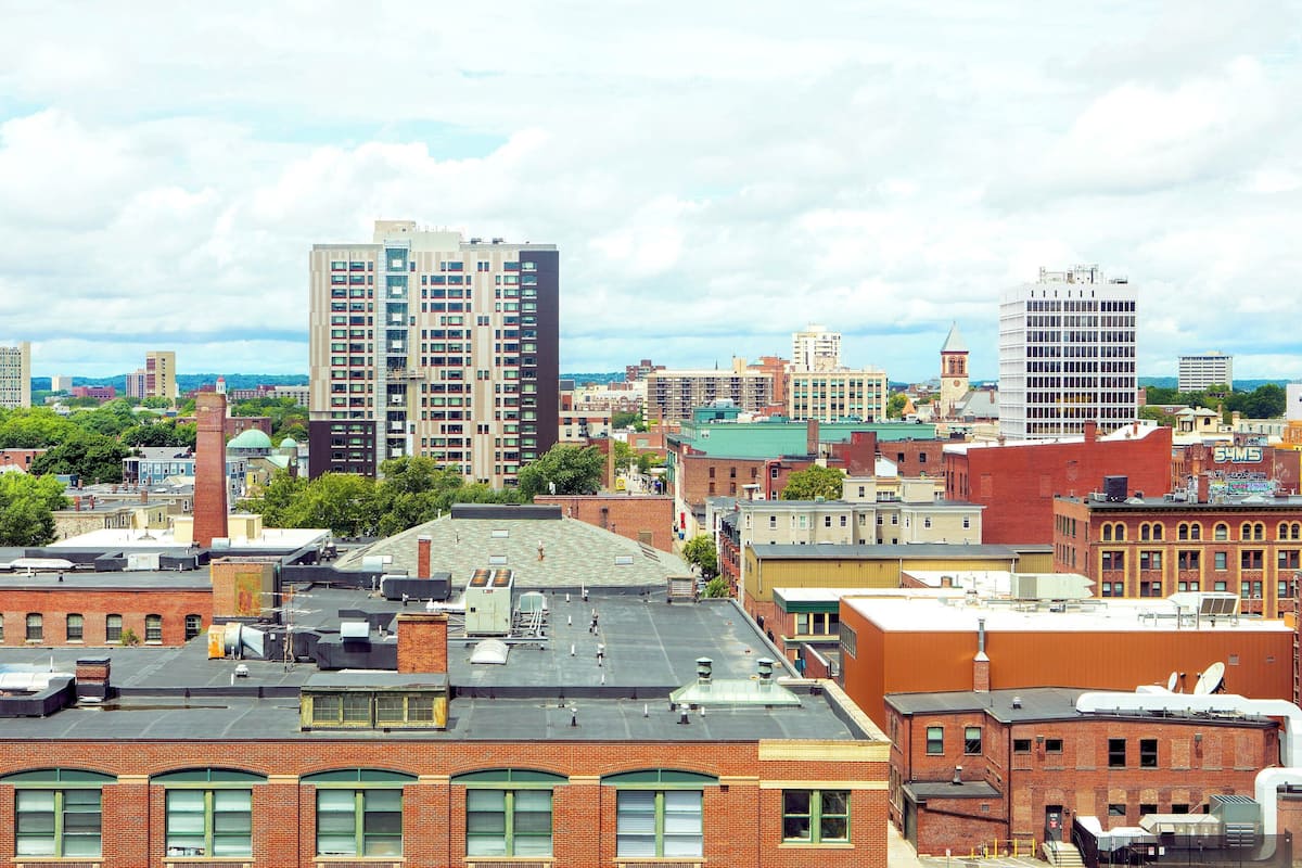A cityscape with various buildings, including a tall modern building and a historic brick building.