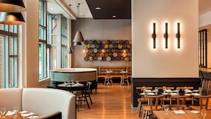 A modern dining area with wooden tables, leather seating, and a wall of decorative plates. - Le Méridien Boston Cambridge (Cambridge)