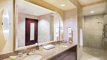 A modern bathroom with two sinks, a large mirror, and a shower area.