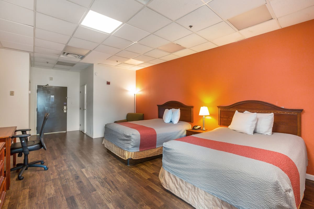 A hotel room with two beds, a desk, and a chair.