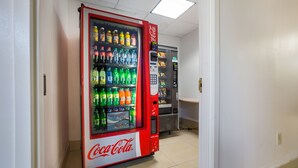 A Coca-Cola vending machine in a hallway with a microwave and a refrigerator in the background. - Budgetel Inns & Suites - Atlanta Galleria Stadium (Atlanta)