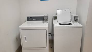 Two front-loading washing machines in a laundry room with a poster on the wall.