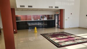 A spacious lobby with a reception desk, a patterned rug, and a yellow caution sign. - Budgetel Inns & Suites - Atlanta Galleria Stadium (Atlanta)