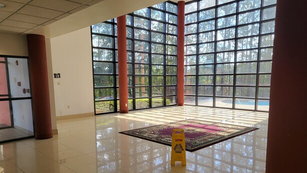 A spacious lobby with large windows, a tiled floor, and a caution sign. - Budgetel Inns & Suites - Atlanta Galleria Stadium (Atlanta)