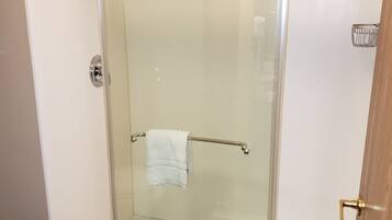 A glass-enclosed shower stall with a towel rack, a visible drain, and a door with a brass handle.