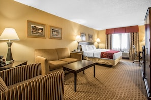 Relax in this inviting room with a comfortable sofa, neatly made bed, and soft lighting from wall-mounted lamps.