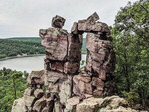 Surrounded by lush greenery and a river, this natural rock formation offers a serene and picturesque setting.