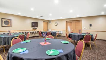 Une salle de conférence avec des tables rondes, des chaises et une horloge au mur.