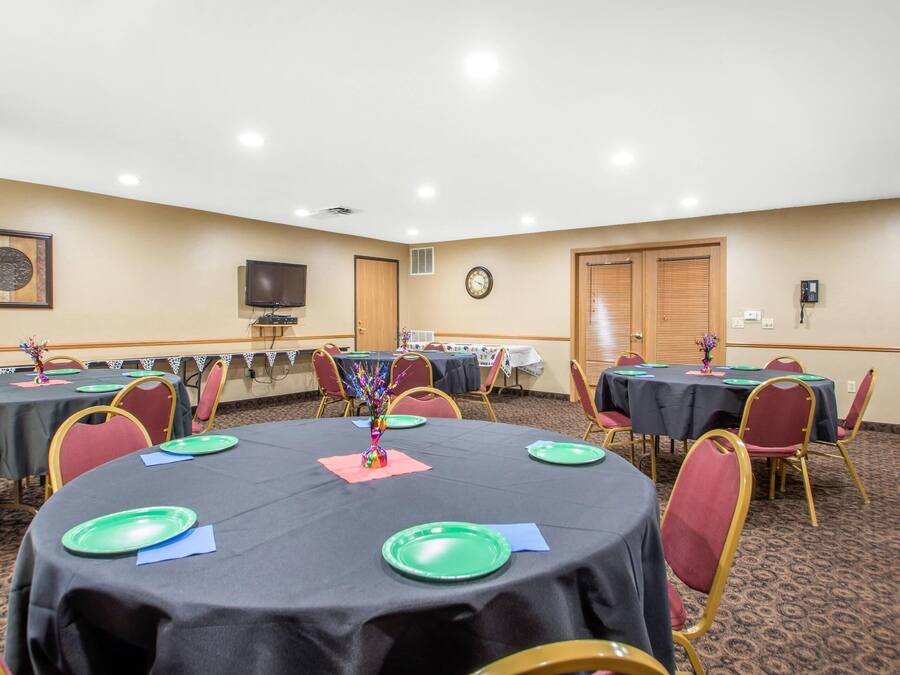Une salle de conférence avec des tables rondes, des chaises et une horloge au mur.