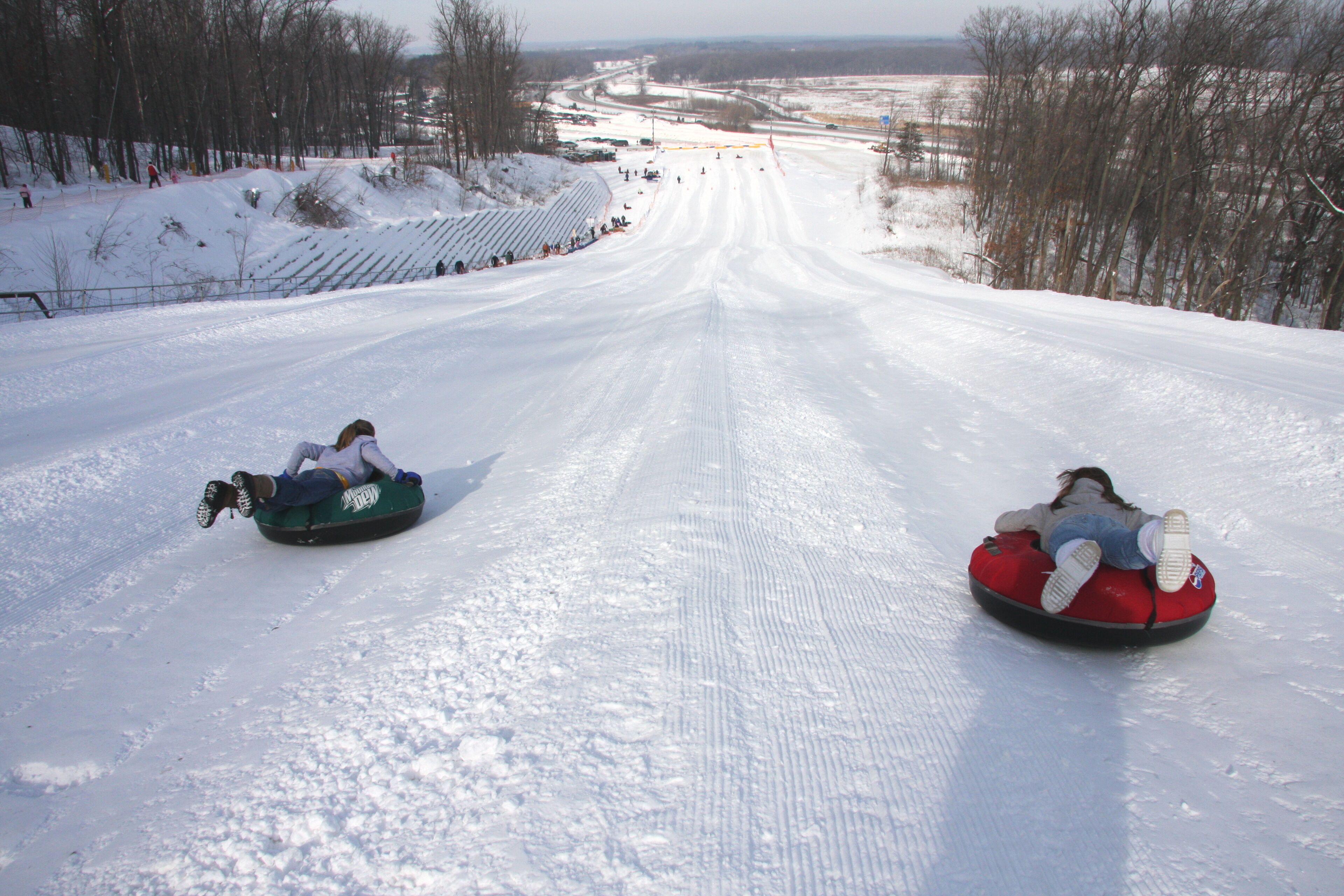 Two people sledding down a snowy slope.