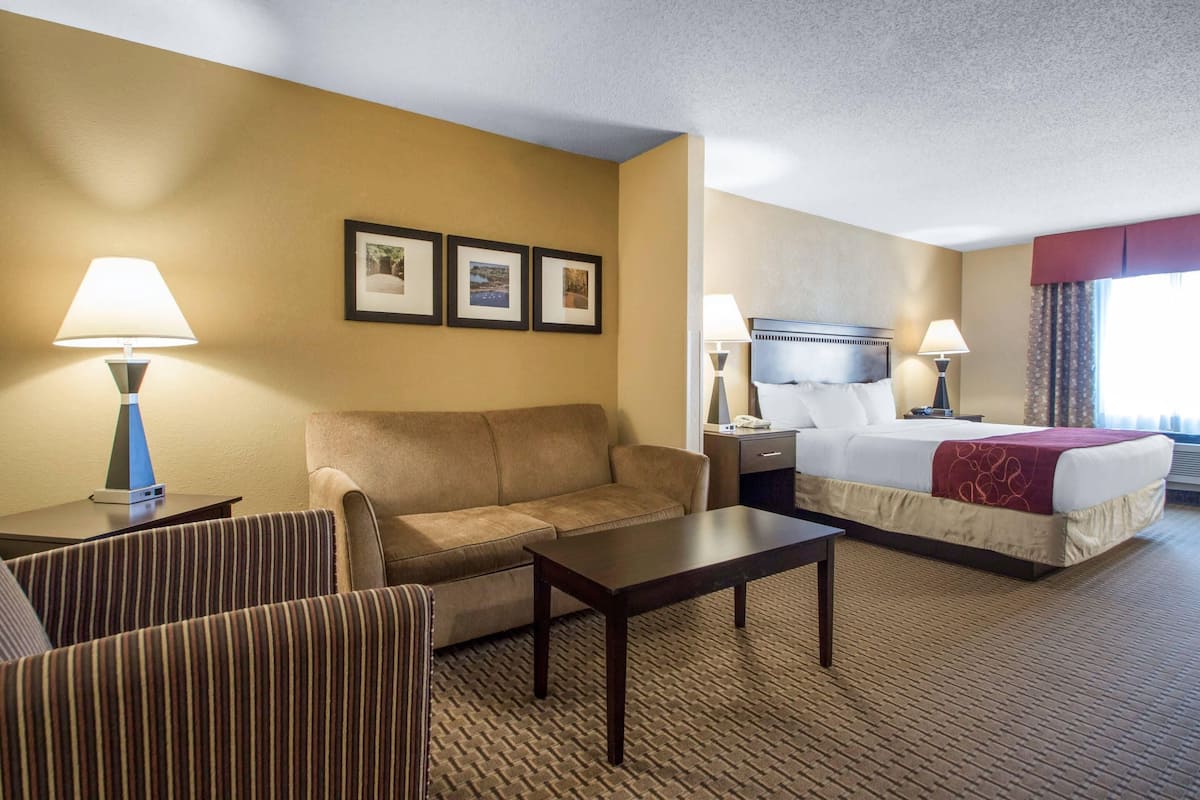 A hotel room with a bed, a sofa, a coffee table, and two lamps.