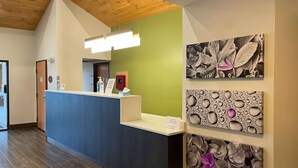 Un espace d’accueil comprenant un comptoir, un mur végétal et des œuvres d’art représentant des feuilles et des fleurs.