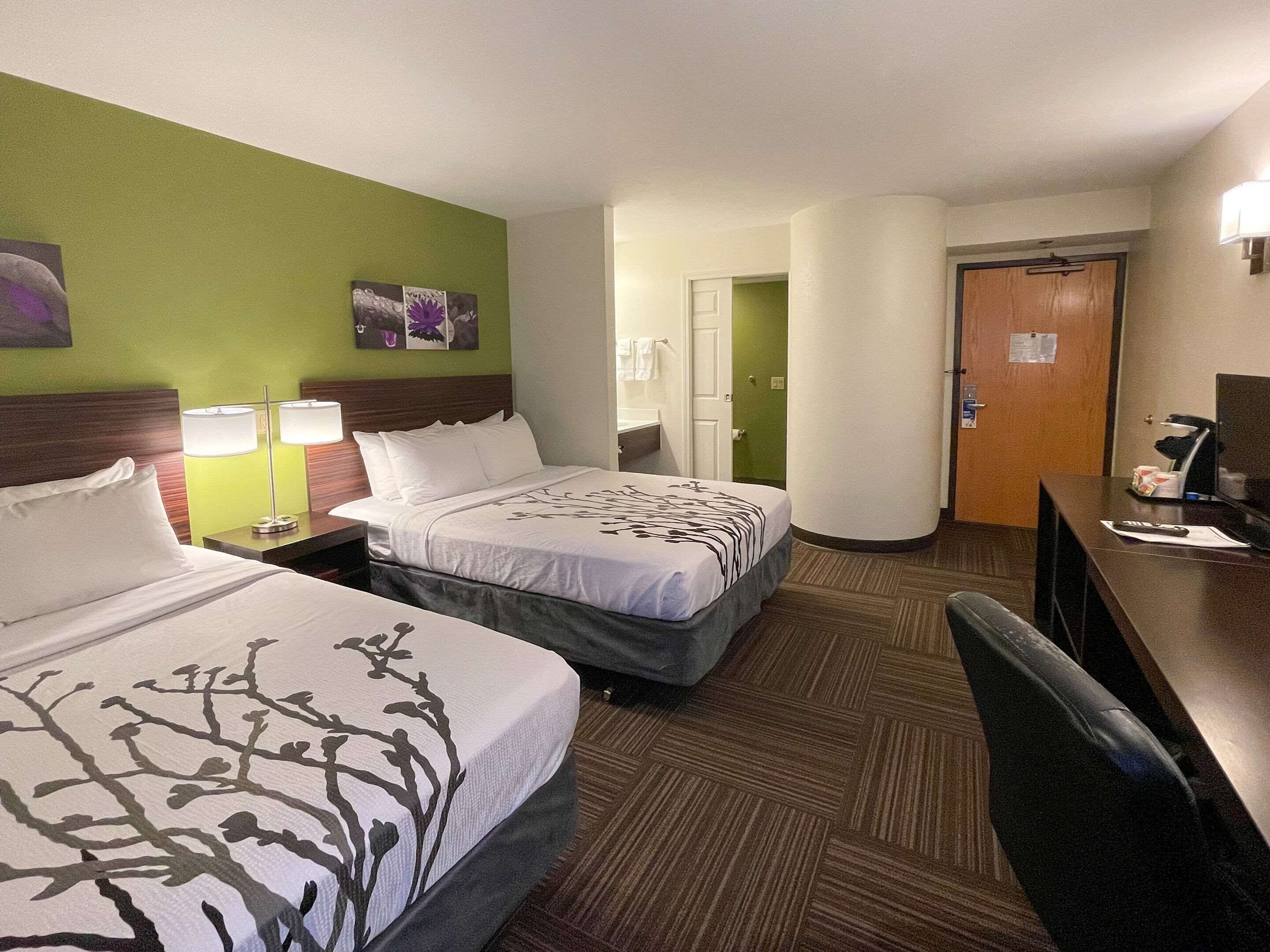 A hotel room with two beds, a desk with a computer, and a chair.