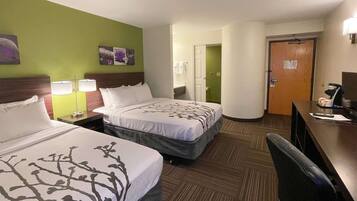 A hotel room with two beds, a desk with a computer, and a chair.