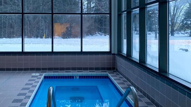 Une piscine avec vue sur un paysage enneigé, grâce à de grandes fenêtres.