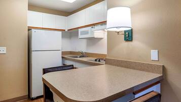 A compact kitchen with white cabinets, a microwave, a sink, and a countertop.