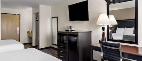 A hotel room with two beds, a desk, a chair, a television, a mirror, and a minibar.