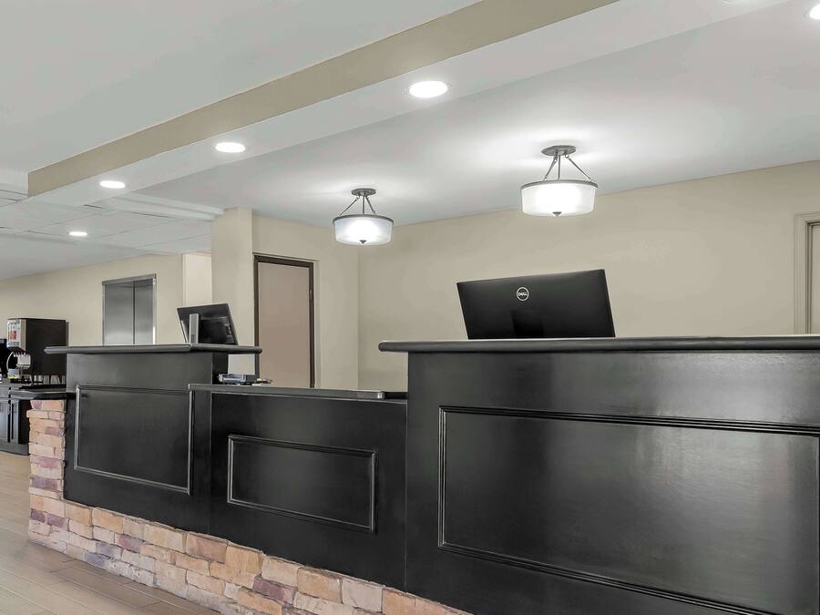 A reception desk with a computer, a coffee machine, and a refrigerator in the background.