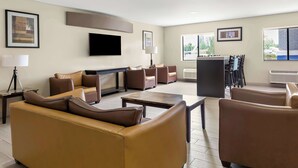 Un hall d’hôtel moderne, doté de canapés en cuir, d’un téléviseur à écran plat et d’œuvres d’art encadrées qui ornent les murs.