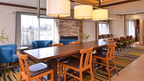 Un espace repas avec une longue table en bois, plusieurs chaises et un tapis coloré à rayures.