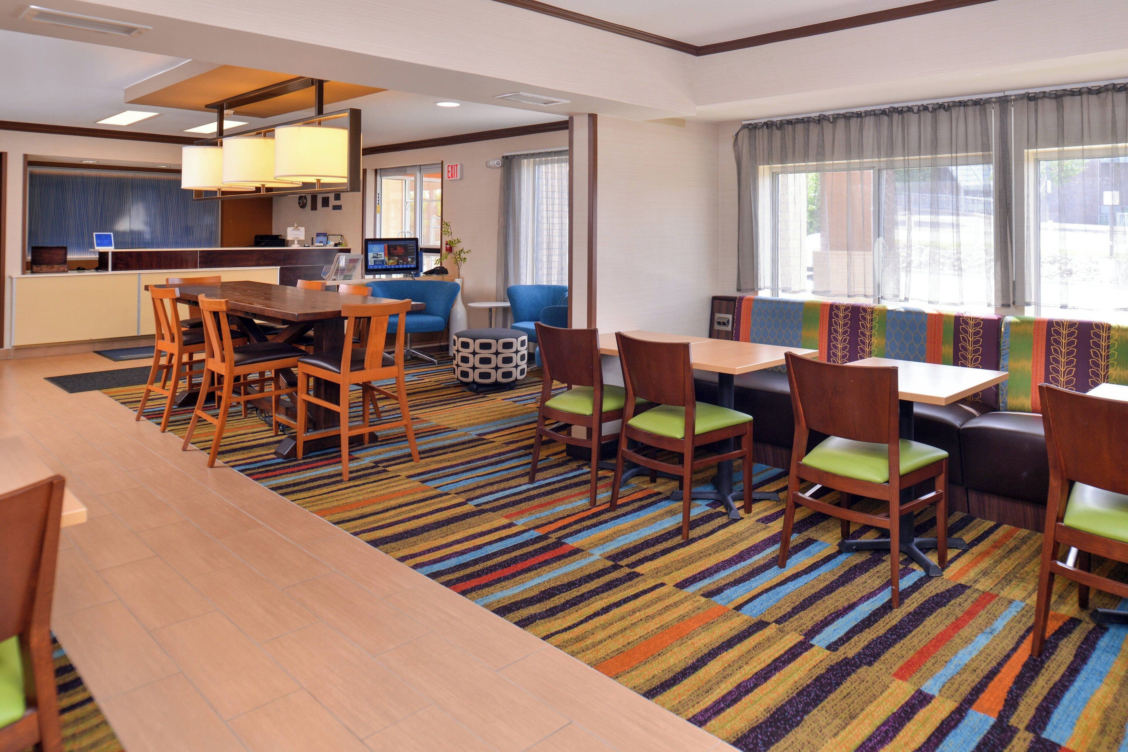 Une chambre d’hôtel comprenant un coin repas, une cuisine et un espace salon avec un tapis rayé aux couleurs vives.