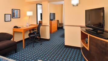 Ein Hotelzimmer mit Schreibtisch, Stuhl, Fernseher und einem kleinen Schrank.