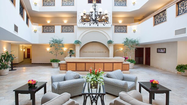 A spacious lobby with a central reception desk, multiple seating areas, and decorative lighting. - Coast Burbank Hotel (Burbank)