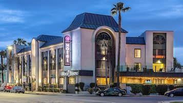 A hotel with a modern architectural design, featuring a prominent arched entrance and a rooftop terrace.