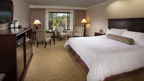 A hotel room with a large bed, a desk with two chairs, a television, and a window with curtains. - Coast Burbank Hotel (Burbank)