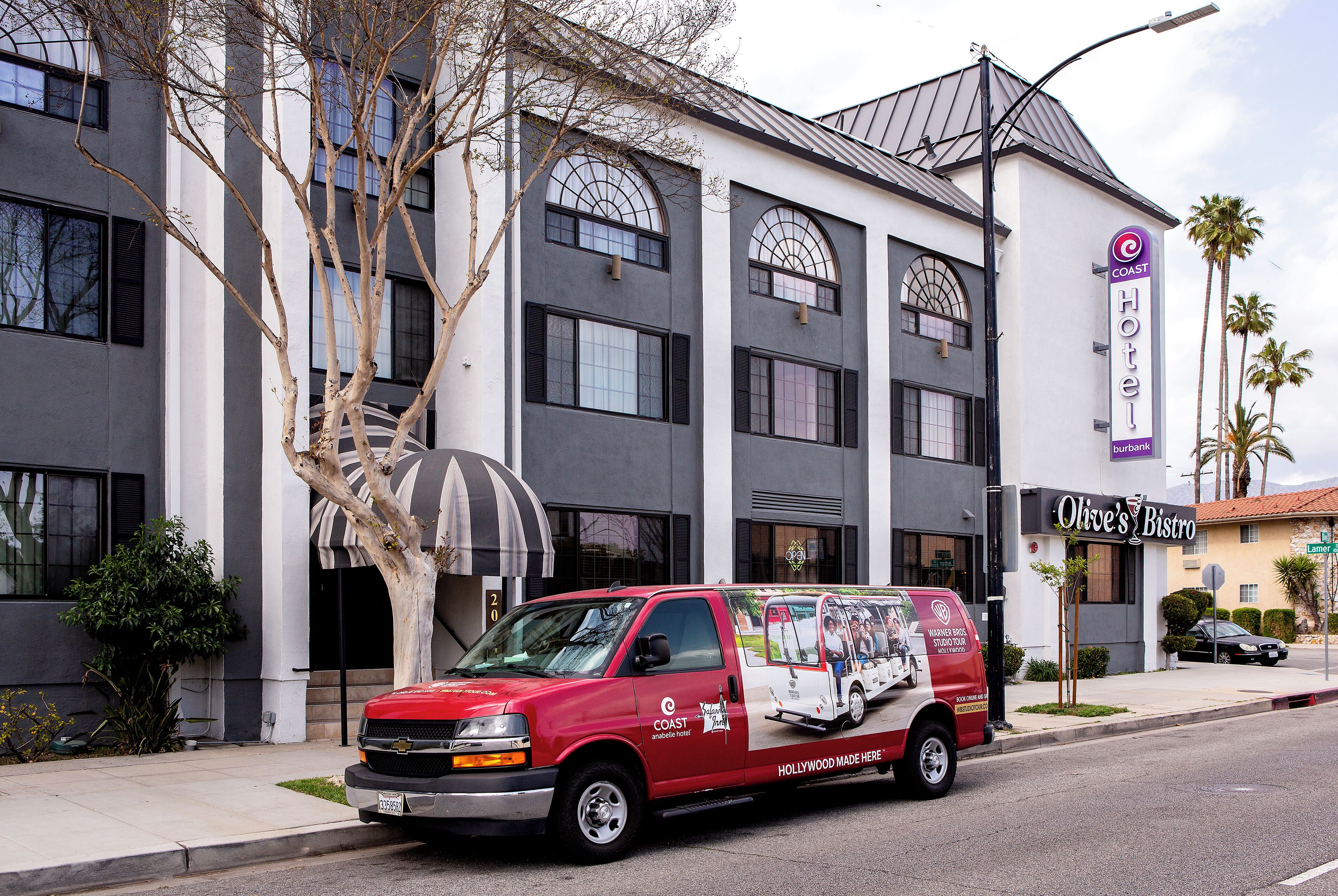A red van parked in front of a hotel with a sign that reads "Coast Hotel."