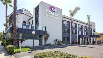 Um hotel moderno com um logotipo em destaque, entrada coberta e área de estacionamento.
