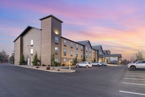 A multi-story hotel with a parking lot and a covered entrance.